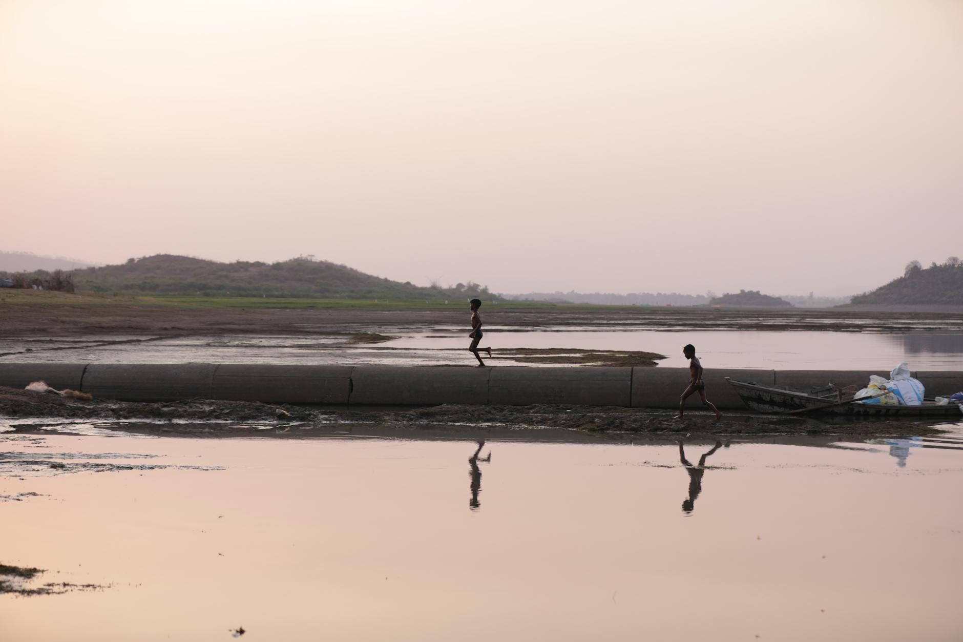 Children running along a serene indian riverbank