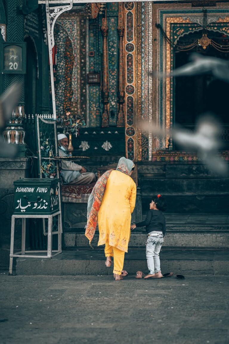 A person in yellow clothing and a child standing outside a mosque.