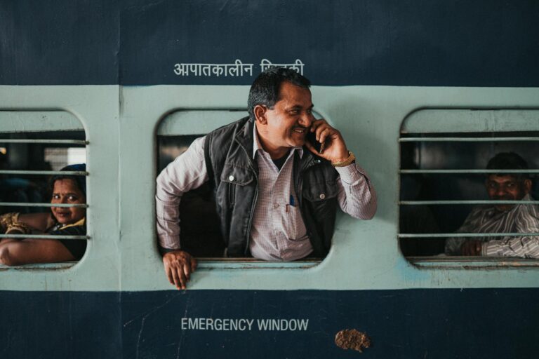 man on phone leaning out of indian train window